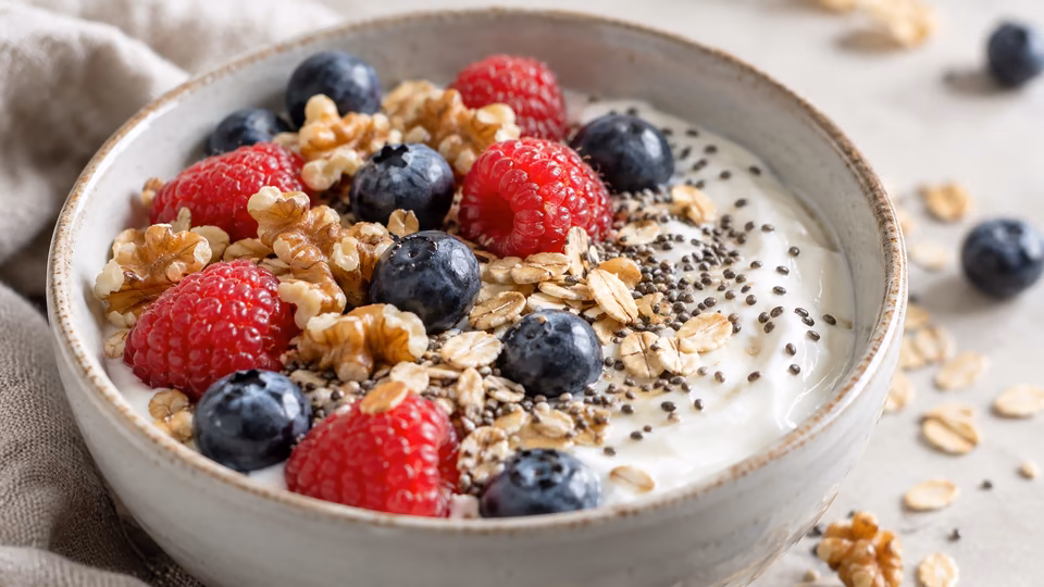 A bowl of oats with berries, nuts and seeds.